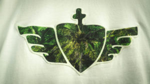 Logoemblem aus bedruckter Baumwolle wurde von Hand vernäht. Handmade, Fair Trade Shirt kaufen